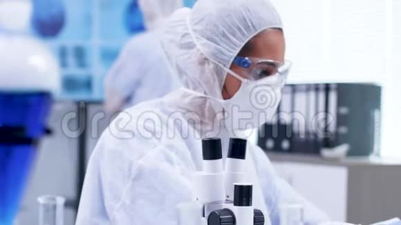 关闭女科学家在实验室中通过莫登显微镜观察的镜头视频的预览图