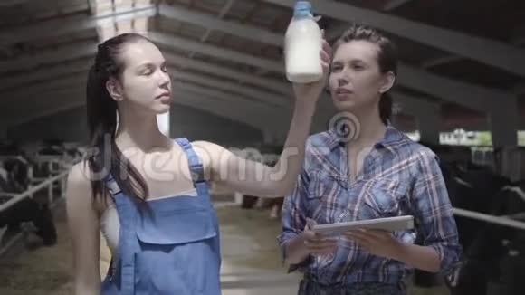 肖像两名专业可爱的女农民工人在奶牛场检查牛奶瓶的质量一个视频的预览图