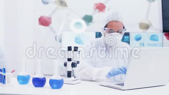 女科学家在现代实验室工作用蓝色液体试管中的试剂和调节显微镜视频的预览图