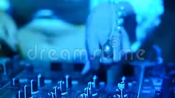 在夜总会迪斯科晚会上Dj混合机控制台的Blur特写DJ双手触摸按钮和滑块播放电子音乐视频的预览图