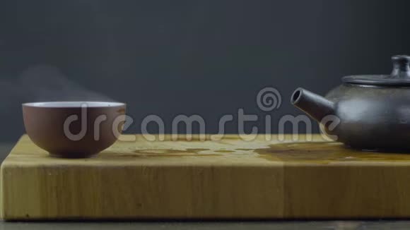 手工制作的宜兴泥茶壶用热茶放在木板上的碗里4k4k录像慢动作24小时视频的预览图