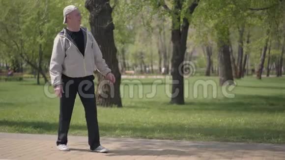 可爱的男孩穿着格子衬衫在公园里滑旱冰他的祖父抓住他拥抱户外活动视频的预览图