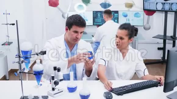 一位穿着白色外套的年轻女科学家和她的助手在现代研究实验室工作视频的预览图
