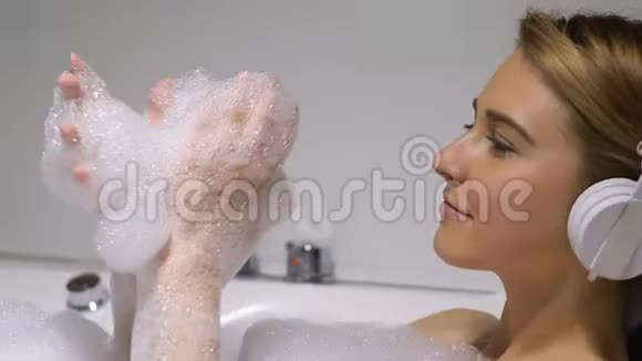 漂亮的女士用耳机听音乐用浴缸做舞蹈动作视频的预览图
