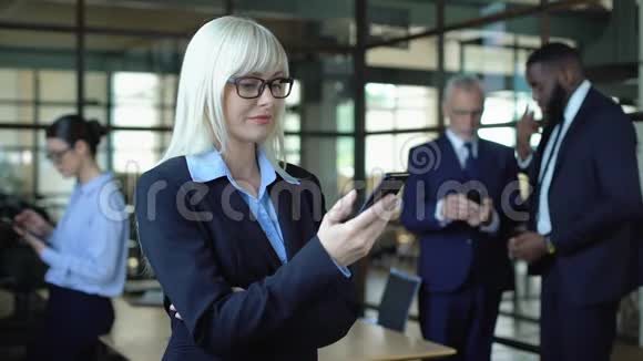 微笑女经理在智能手机上阅读电子邮件滚动商业新闻应用程序视频的预览图