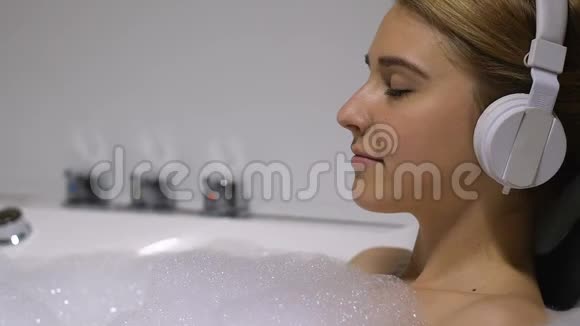 年轻美丽的女人听着耳机里最喜欢的音乐享受着沐浴视频的预览图