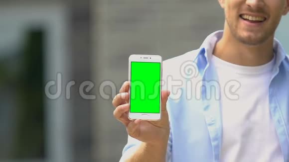 年轻开朗的男性显示智能手机绿色屏幕在线应用现金返还视频的预览图