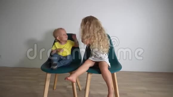 男孩和女孩坐在椅子上用手互相撞击视频的预览图