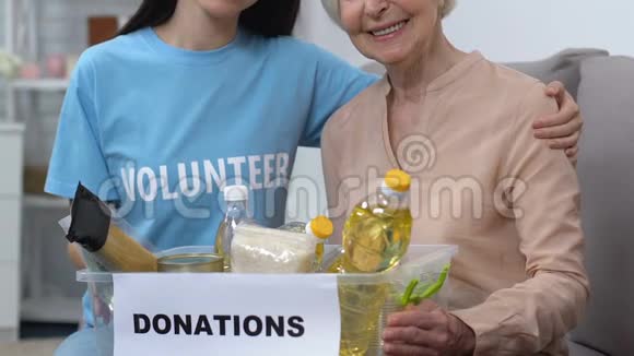 微笑的年轻志愿者和老年女性拿着食物的盒子社会帮助视频的预览图