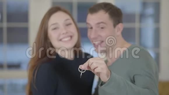 一对幸福的新婚夫妇的肖像在镜头前展示了一套新房子或公寓的钥匙视频的预览图