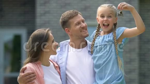 开朗的父母和女孩子拿着钥匙在镜头前微笑购买视频的预览图