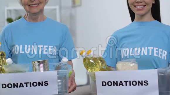 微笑青年和老年女性志愿者拿着装有食物的盒子捐款视频的预览图
