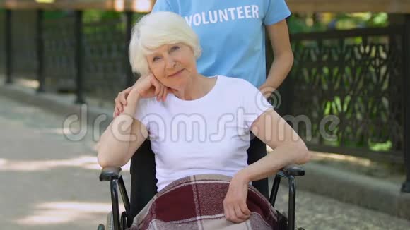 义工扶助轮椅上的残疾老人白天在医院公园视频的预览图