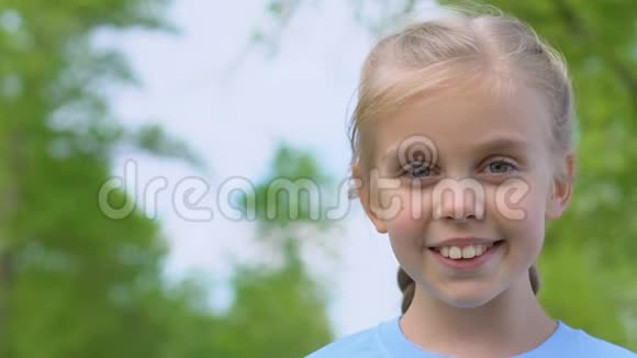 美丽的小女孩在公园的镜头上微笑热爱大自然快乐的童年视频的预览图