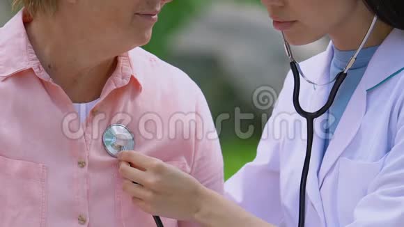 医生带着听诊器在公园的长凳上检查老女性病人的心跳视频的预览图