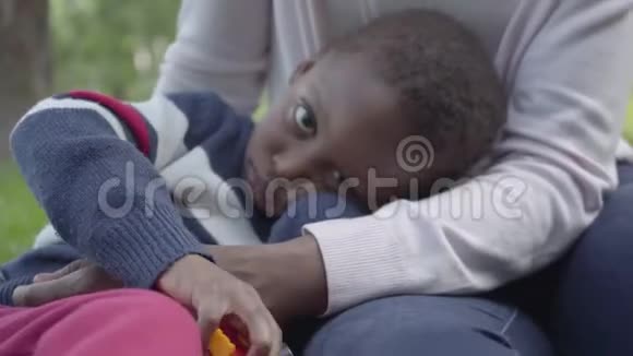 一位可爱的非裔美国妇女在公园里用塑料玩具和她的小儿子玩耍年轻的母亲视频的预览图