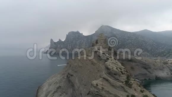 神圣的在海中飞过一块岩石和漂浮的船多云天气视频的预览图