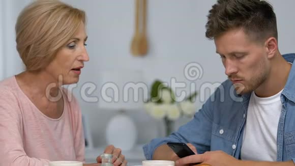 儿子无视与母亲的现场沟通在智能手机上聊天冲突视频的预览图