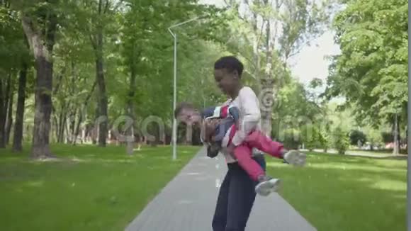非裔美国人的母亲正把儿子搂在怀里妈妈和孩子周末在公园里放松视频的预览图