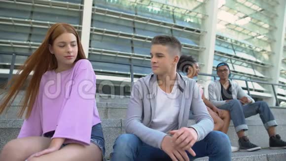 青少年学生坐在靠近迷人的年轻女性的地方第一次浪漫的同情视频的预览图