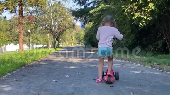 快乐的小孩子可爱的女孩学习骑和平衡的推滑板车视频的预览图