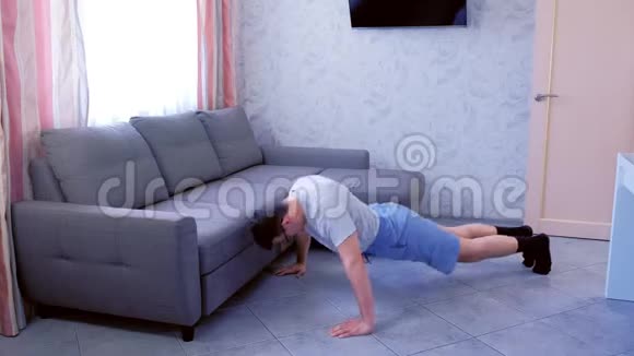 有趣的书呆子正在做俯卧撑运动并从疲惫的家里跌倒在地板上视频的预览图