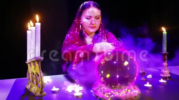 一个吉普赛女人在一个魔法沙龙里在一个水晶球和一个比特币标志上猜测烟雾视频的预览图