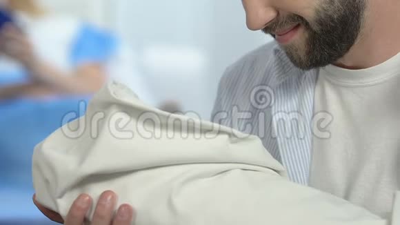 微笑的父亲抱着新生儿在医院看着婴儿父母的幸福视频的预览图