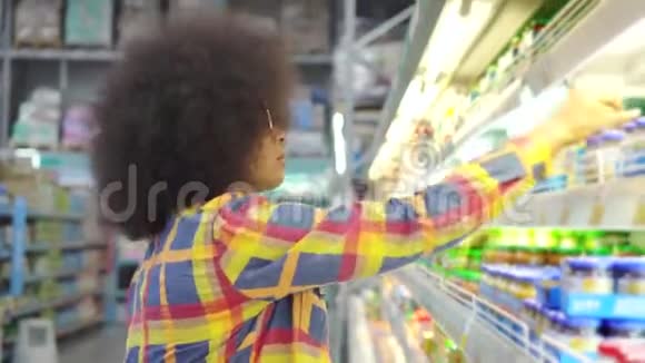 美丽的非洲裔美国妇女有非洲发型的商店选择酸奶视频的预览图