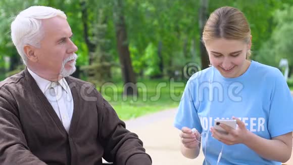 女志愿者给孤独老人送耳机在公园听音乐视频的预览图