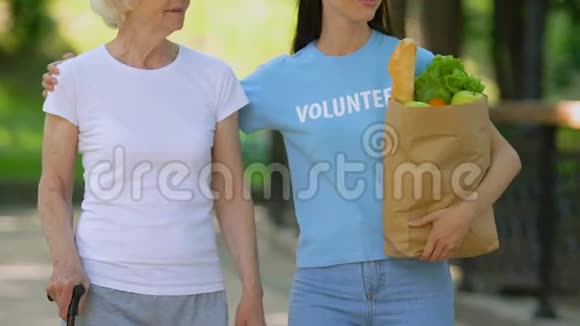 志愿者带着拐杖给老残疾女士送食物在医院公园散步视频的预览图