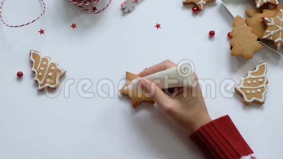 为圣诞节做姜饼饼干女人的手画饼干上有白色的釉顶部视图视频的预览图