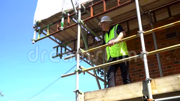 有脚手架和蓝天建筑工地的男建筑工人视频的预览图