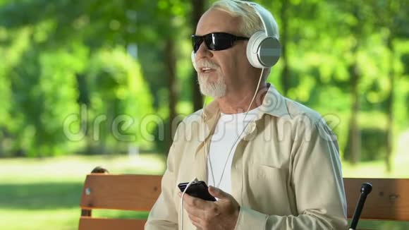 有视觉障碍的老人用耳机听音乐视频的预览图