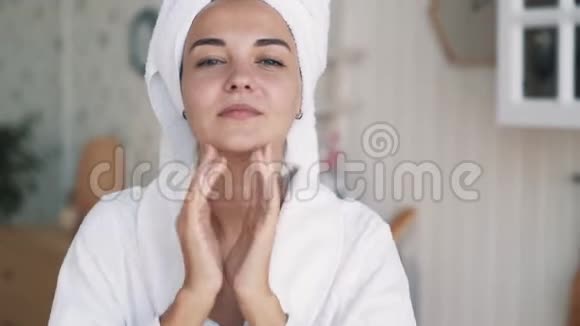 贴身穿浴袍的女孩头上有毛巾能让面部按摩恢复活力视频的预览图