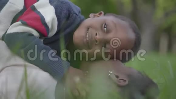 一个小可爱的非裔美国男孩躺在他母亲的顶部玩她的耳环和微笑母亲视频的预览图