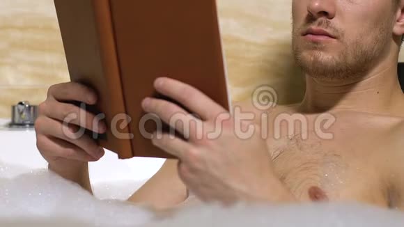 浴缸里的帅气男性阅读书籍爱好和点心自由活动视频的预览图