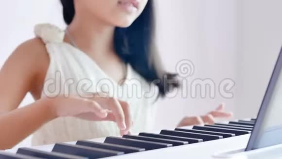 穿着白色连衣裙的贴身女孩在清晨阳光下弹钢琴幸福地微笑着视频的预览图