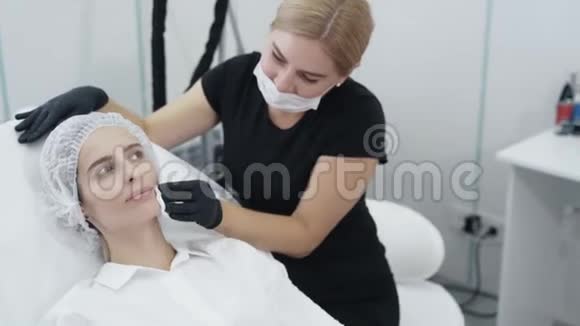 一次性口罩中的慢动作美容师为患者面部准备美容手术治疗视频的预览图