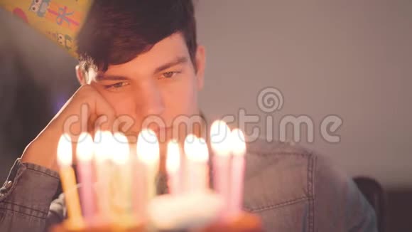 肖像孤独悲伤的男孩坐在小蛋糕前面上面有点燃的蜡烛不快乐的人有生日视频的预览图