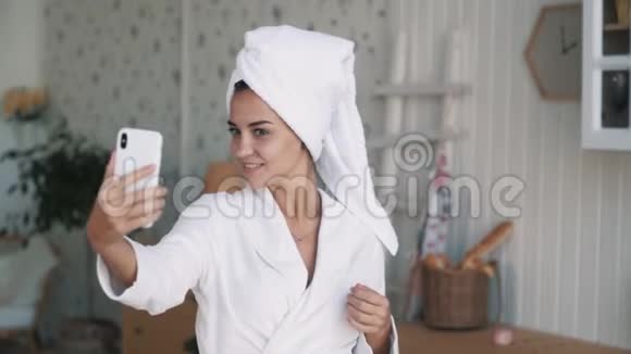 穿着浴袍头上有毛巾的女人在电话里自拍慢动作视频的预览图