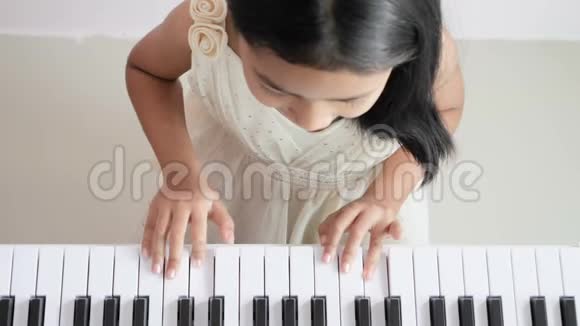 顶景女孩穿着白色连衣裙用慢动作弹钢琴视频的预览图