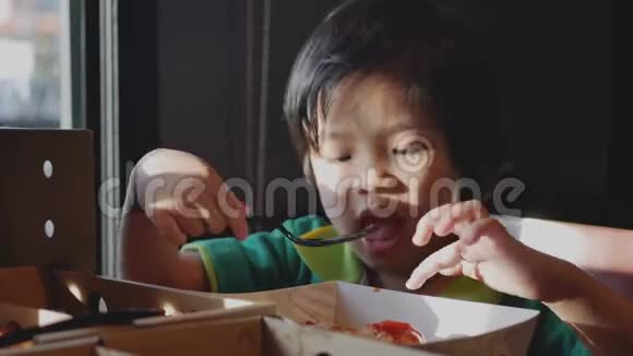 一个亚洲小女孩喜欢在一家餐馆用手和叉子在一块披萨上吃番茄酱视频的预览图