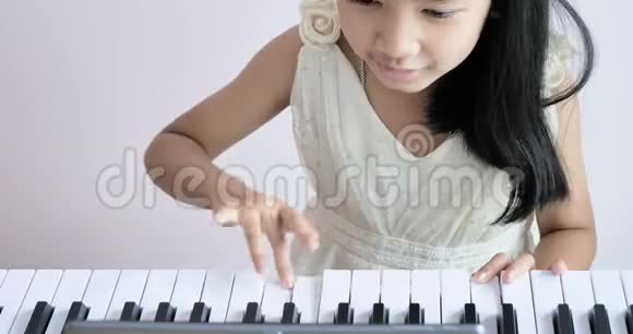 穿着白色连衣裙的贴身女孩在清晨阳光下弹钢琴幸福地微笑着视频的预览图