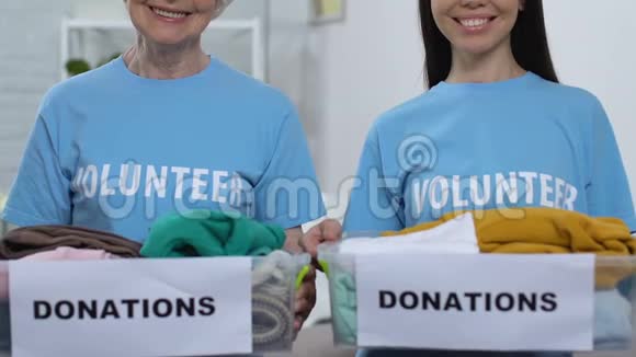 善良的女士志愿者展示盒子和衣服相机捐赠穷人视频的预览图