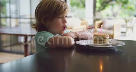 在厨房的餐桌上男孩在煎饼上吹蜡烛视频的预览图