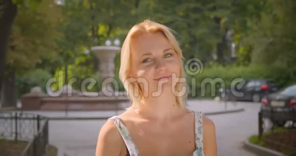 一位成年白种人金发女子的特写镜头她开心地笑着看着站在公园户外的摄像机视频的预览图