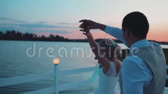 情侣们正在美丽的码头上跳舞美丽的日落镜头绕着恋人转视频的预览图