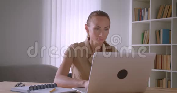 优雅的白种人女商人分析笔记本电脑上的数据在办公室里变成了相机和手表视频的预览图