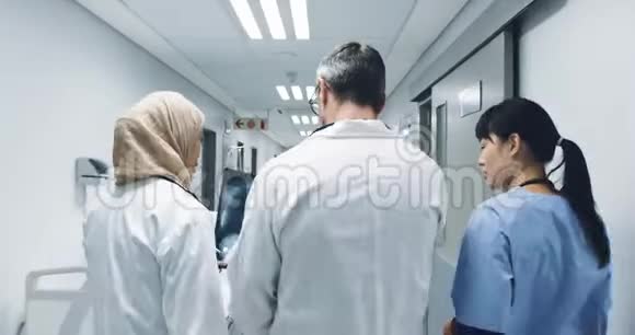 三位医生在医院走廊步行的背面视频的预览图